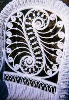 Painted Victorian reed wicker rocker with serpentine arms, beads and curlicues.