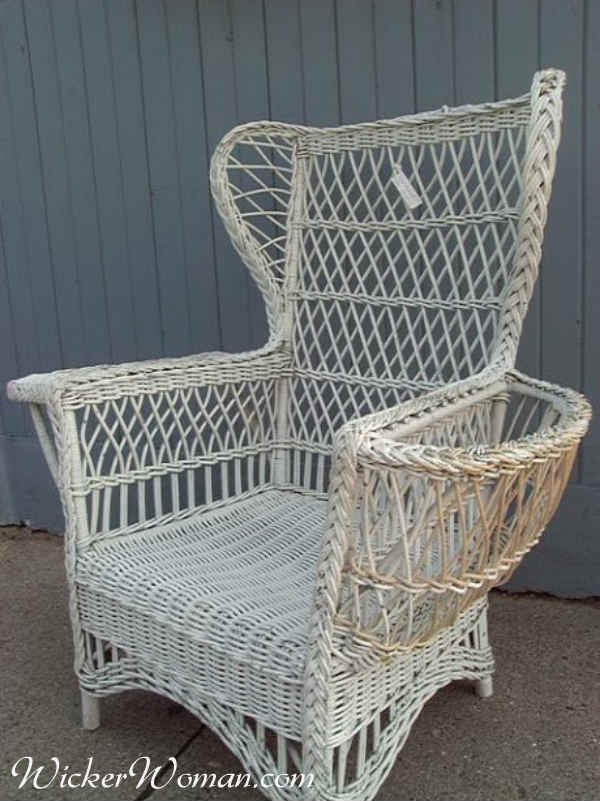 White painted 1910s reed wicker Bar Harbor chair with woven seat, open-weave back and sides, with wings on back and left side magazine rack.  