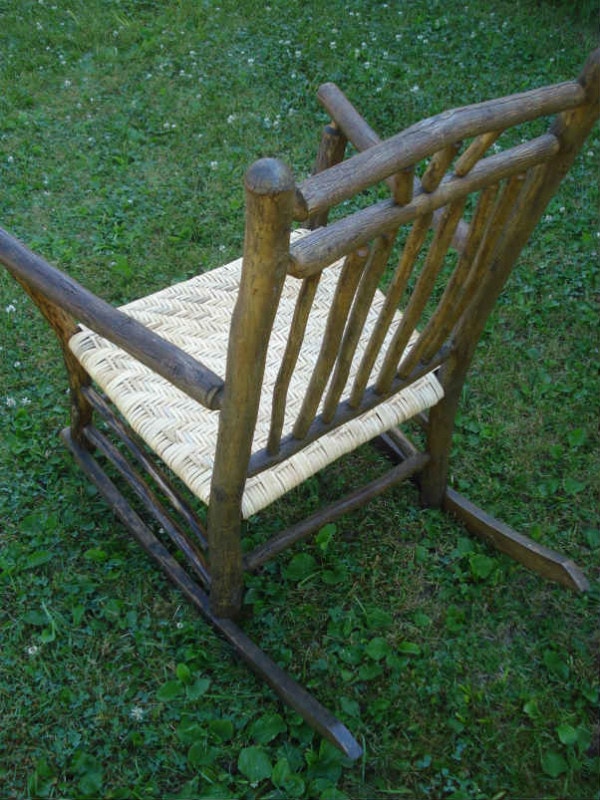 Back of a rustic hickory rocker with wide binding cane seat.