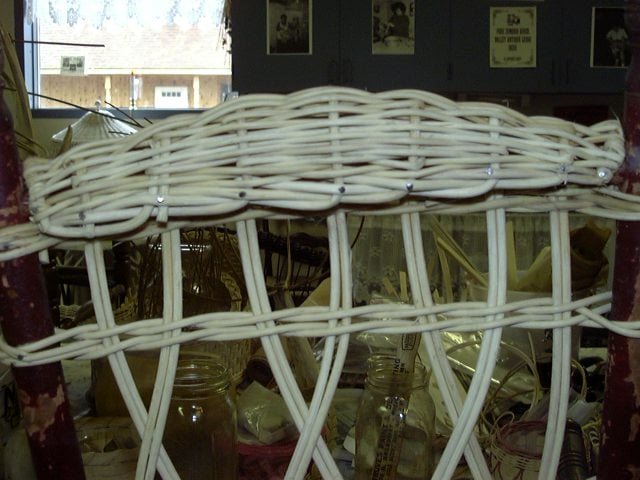 Vertical spokes have been completed and the rolled, arched headrest has also been woven and ends have been braided into place and attached to frame.