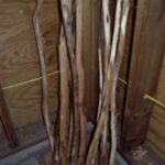 Several diamond willow poles with bark removed sitting in a corner.