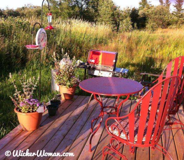 Hummingbird feeders and red, metal patio furniture on the deck.