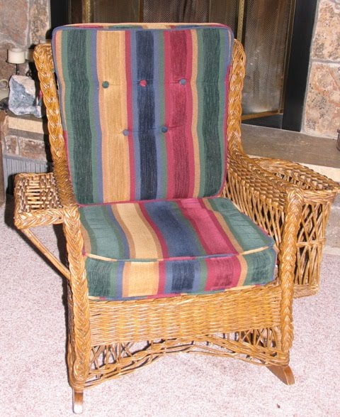 Rattan reed 1915 Bar Harbor style wicker rocker with arms and side magazine rack. 
