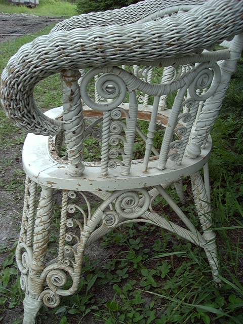 Victorian wicker chair, heavily adorned and embellished with curlicues, arrow weave serpentine arms, and cane webbing seat needing to be replaced.