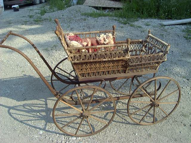 1880s fancy upholstered wicker baby perambulator with wooden wheels, and steel springs, adorned with heavy wicker embellishments. 