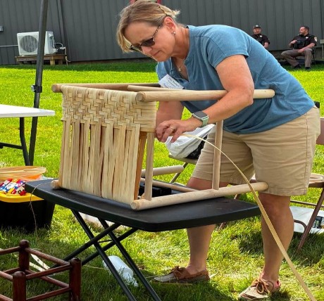 Patty Younger of My Younger Life Caning in VA, is demonstrating splint seat weaving at a festival.